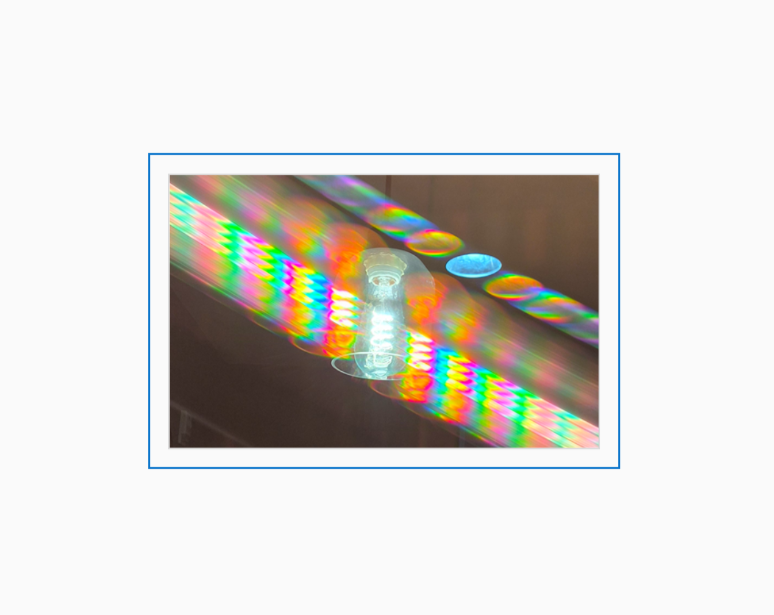 Diffraction grating photograph of a hotel lobby light fixture, rendered in spectral color against a dim background.