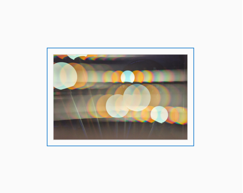 Diffraction grating photograph of a wall-mounted light fixture in a hotel elevator bank, rendered with rainbow spectral color streaks.