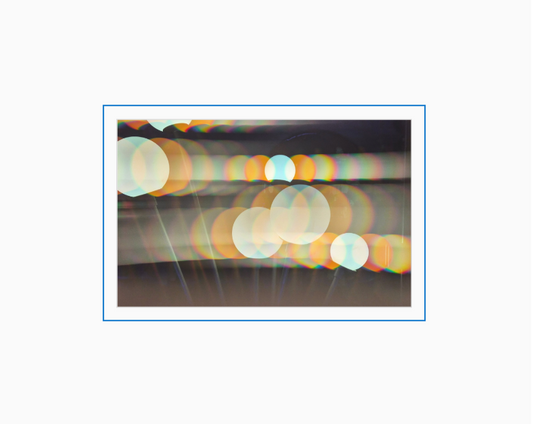 Diffraction grating photograph of a wall-mounted light fixture in a hotel elevator bank, rendered with rainbow spectral color streaks.