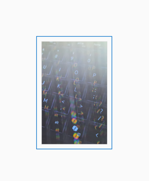 Diffraction grating photograph of a backlit computer keyboard with sunlight streaming across it, rendered in spectral color.